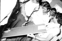Students signing on a board titled “In Memory..” and “Mardi Gras ‘83”