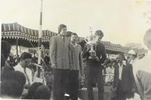 A competition winner holds a trophy on the podium