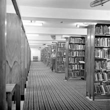 A person browsing through a section of books in the Central Library, 1967