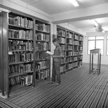 A person browsing through a section of books in the Central Library, 1967