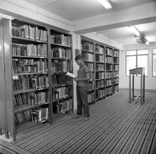 A person browsing through a section of books in the Central Library, 1967