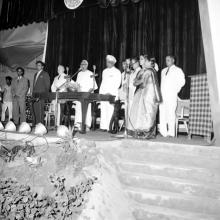 The dignitaries on the dais stand for the invocation before the commencement of the event