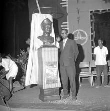 An individual who is possibly the sculptor, poses with the bust of Dr. A. L. Mudaliar