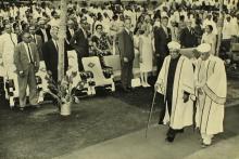 The audience stands as Dr. A. L. Mudaliar escorts Sir C. V. Raman to the dais 