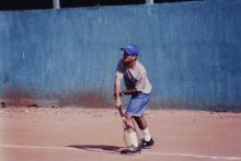 A tennis player follows through after hitting a ball, 1999