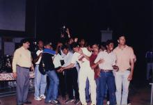 An elated group of students lift a trophy, 1999