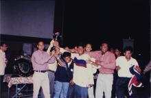 A jubilant team lifts a trophy, 1999
