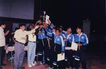 A group of ecstatic students lift a trophy, 1999
