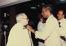 Mr. Russi Mody being helped with convocation robes, 1989