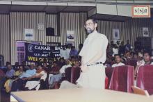 A man in the audience addresses people on the dais 